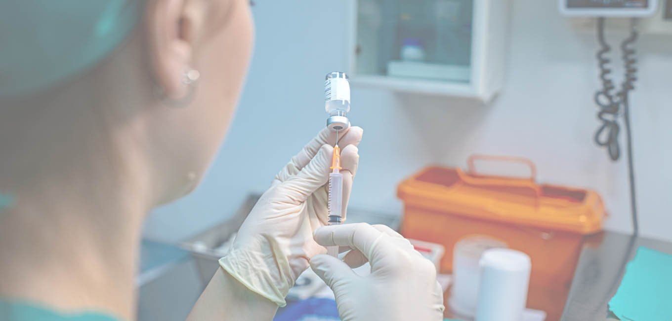 Девушка-медик заполняет шприц лекарством из ампулы